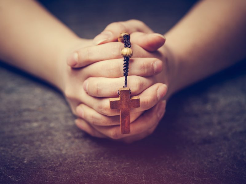 Woman praying with a rosary.